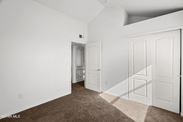 unfurnished bedroom featuring a closet, high vaulted ceiling, and dark carpet