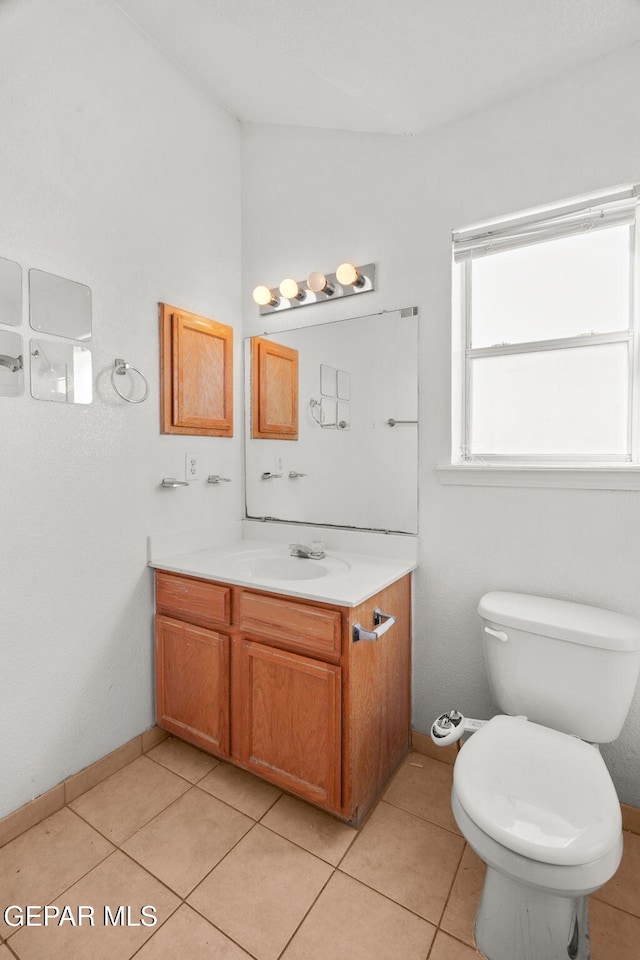 bathroom with toilet, vanity, and tile patterned flooring