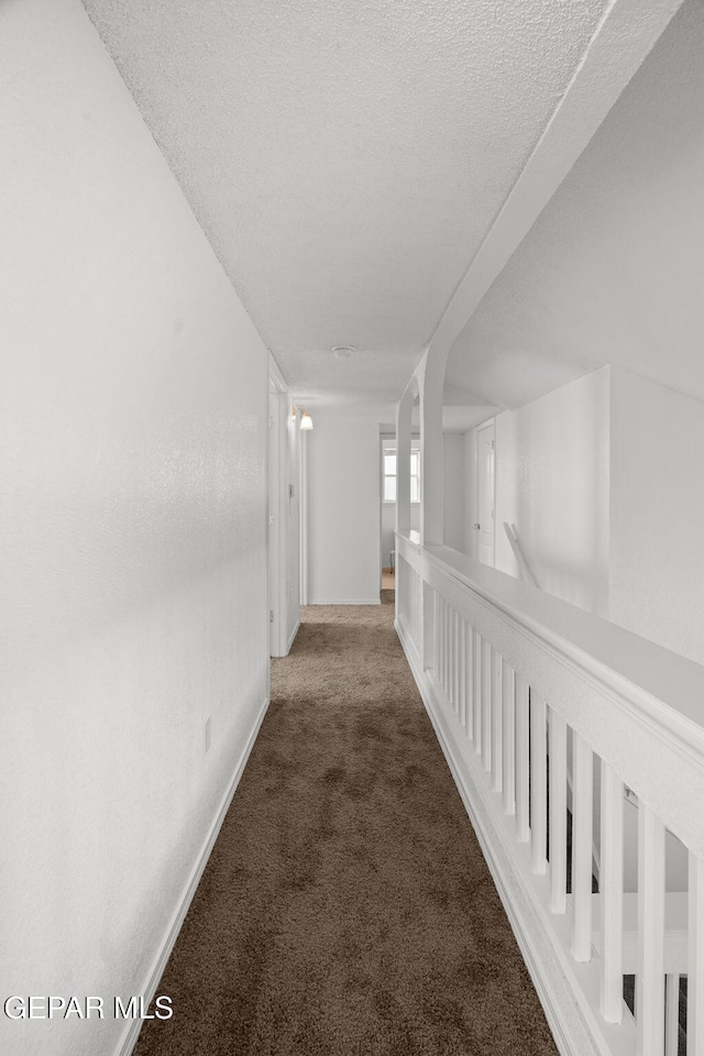 hall with carpet flooring and a textured ceiling