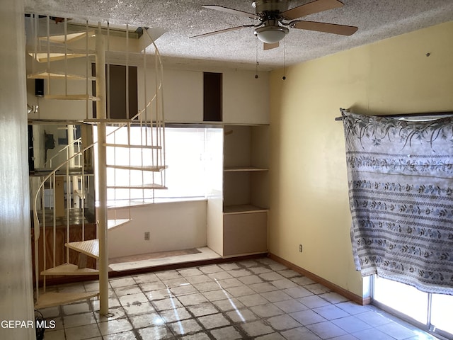 spare room featuring a textured ceiling, ceiling fan, and light tile patterned flooring