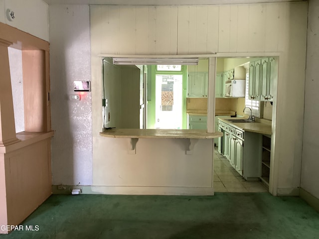 kitchen featuring sink, a breakfast bar area, light carpet, and kitchen peninsula