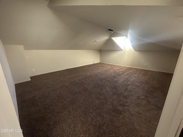 bonus room with lofted ceiling and dark carpet