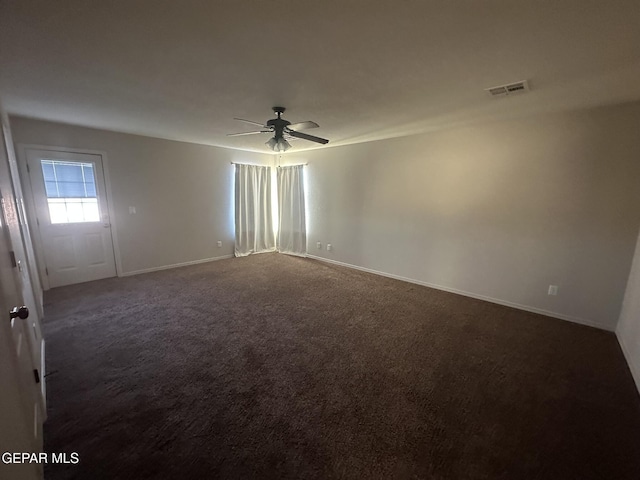 empty room featuring ceiling fan and dark colored carpet