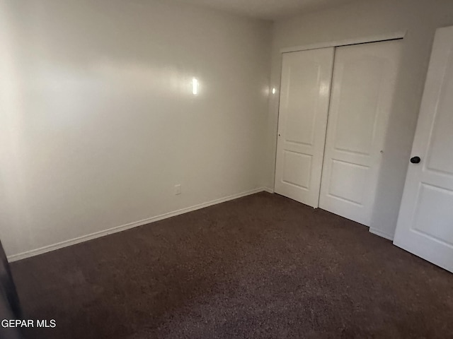 unfurnished bedroom featuring a closet and dark colored carpet