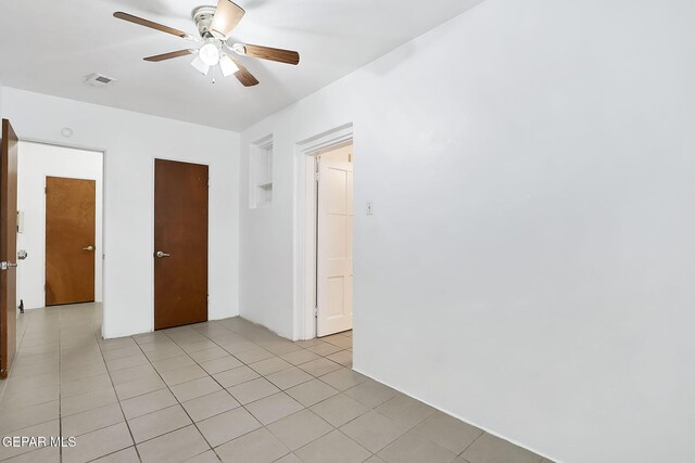 tiled empty room featuring ceiling fan