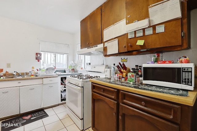 kitchen with sink, white appliances, and light tile patterned flooring