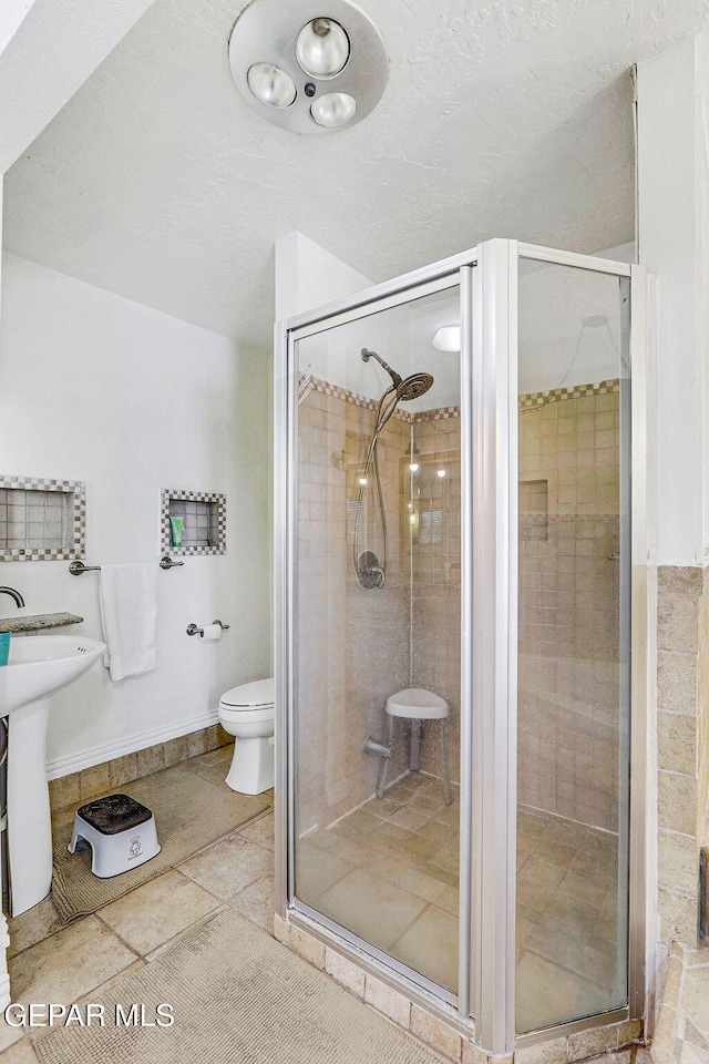 bathroom featuring sink, an enclosed shower, and toilet