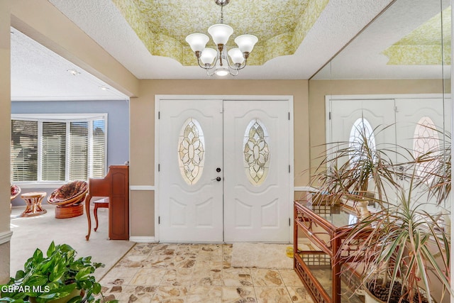 entrance foyer with a raised ceiling and a notable chandelier