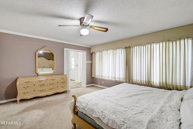 bedroom with ceiling fan, connected bathroom, light carpet, and a textured ceiling