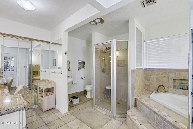 bathroom with tile patterned flooring, a textured ceiling, plus walk in shower, and toilet