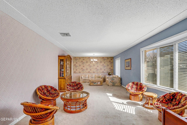 sitting room with carpet, a textured ceiling, and an inviting chandelier