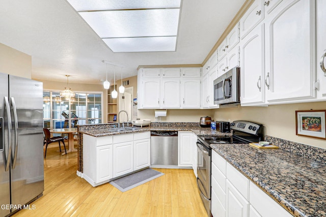 kitchen featuring white cabinetry, sink, hanging light fixtures, kitchen peninsula, and stainless steel appliances