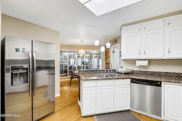 kitchen featuring sink, hanging light fixtures, appliances with stainless steel finishes, kitchen peninsula, and white cabinets