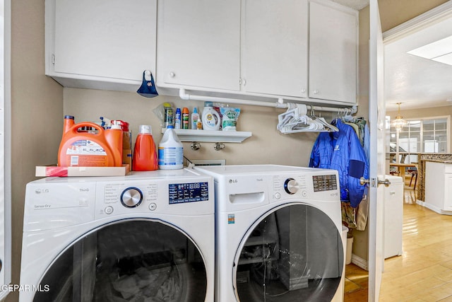 clothes washing area with light hardwood / wood-style flooring, washing machine and dryer, and cabinets