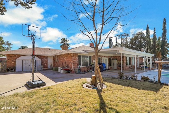 ranch-style home with a storage shed, a front lawn, and a patio area