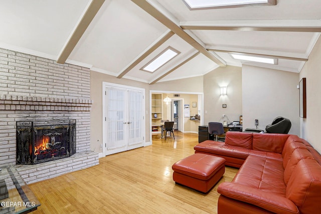 living room with hardwood / wood-style flooring, lofted ceiling with skylight, and a brick fireplace