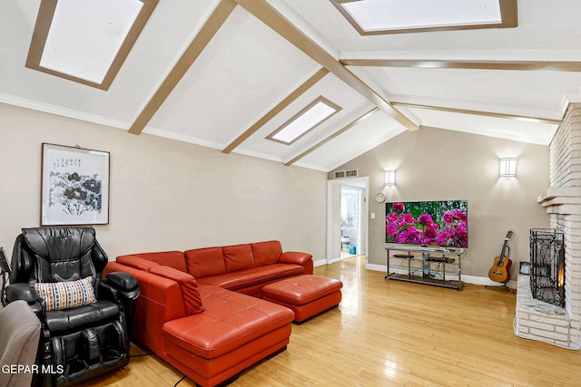 living room with a brick fireplace, hardwood / wood-style flooring, and vaulted ceiling with skylight