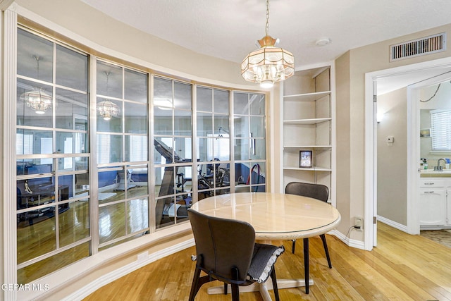 dining room with sink, built in features, and light wood-type flooring