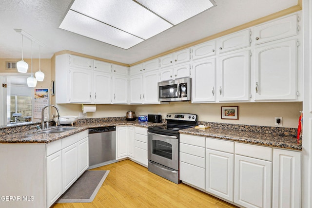 kitchen featuring stainless steel appliances, sink, hanging light fixtures, and white cabinets