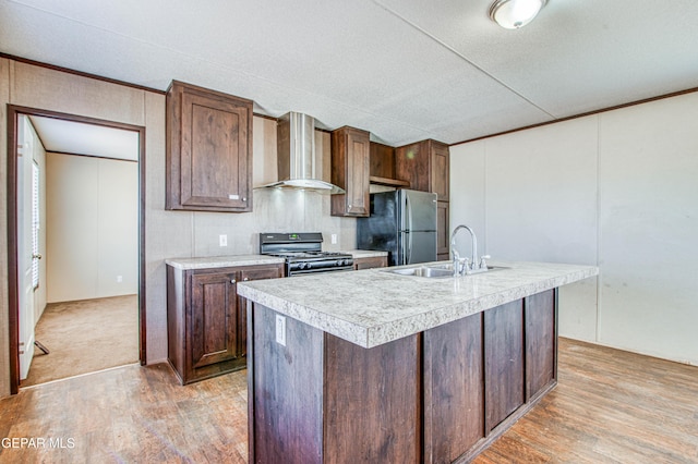 kitchen featuring sink, light hardwood / wood-style floors, black appliances, an island with sink, and wall chimney exhaust hood