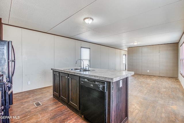 kitchen featuring dark hardwood / wood-style floors, black dishwasher, sink, a kitchen island with sink, and dark brown cabinetry