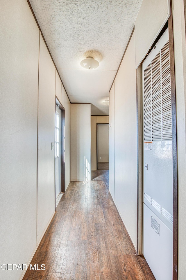 hallway featuring dark wood-type flooring and a textured ceiling