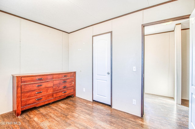 bedroom featuring hardwood / wood-style floors, ornamental molding, and a closet