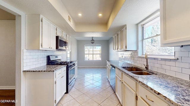 kitchen with light stone countertops, appliances with stainless steel finishes, sink, and light tile patterned floors