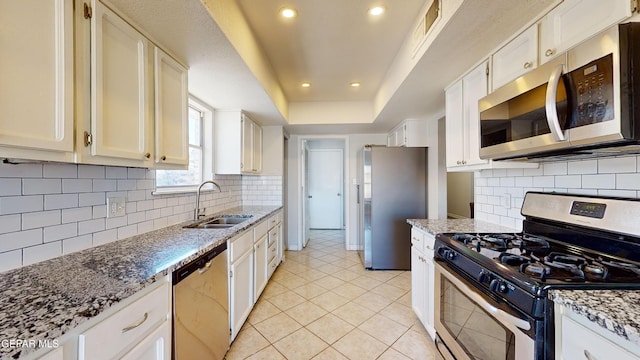 kitchen featuring white cabinetry, sink, a raised ceiling, and appliances with stainless steel finishes