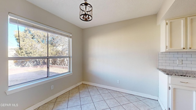 unfurnished dining area featuring light tile patterned flooring and an inviting chandelier