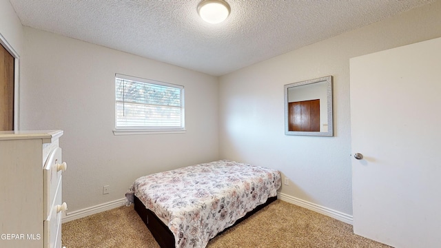 bedroom with light colored carpet and a textured ceiling