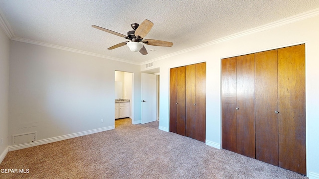 unfurnished bedroom featuring ceiling fan, ornamental molding, a textured ceiling, light colored carpet, and multiple closets