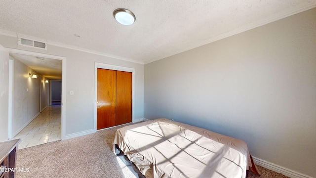 carpeted bedroom with ornamental molding, a closet, and a textured ceiling