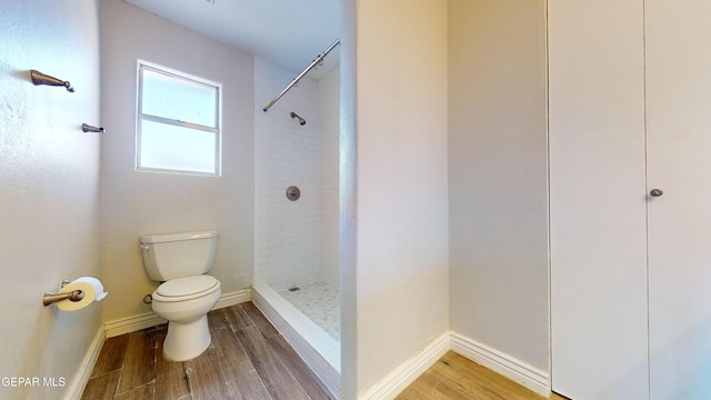 bathroom with a tile shower and toilet