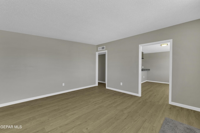 unfurnished bedroom with hardwood / wood-style flooring, a spacious closet, and a textured ceiling