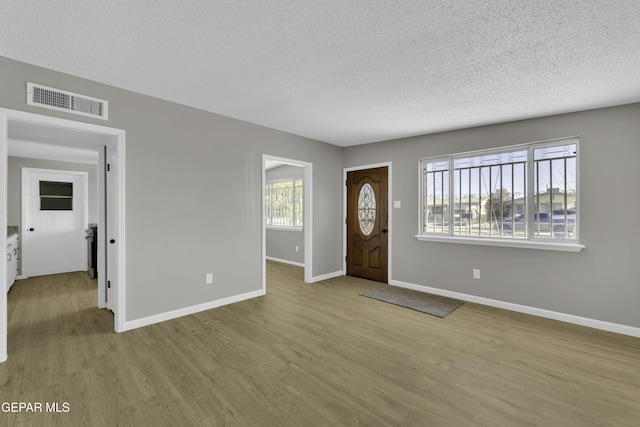 entryway with a textured ceiling, light hardwood / wood-style flooring, and a healthy amount of sunlight