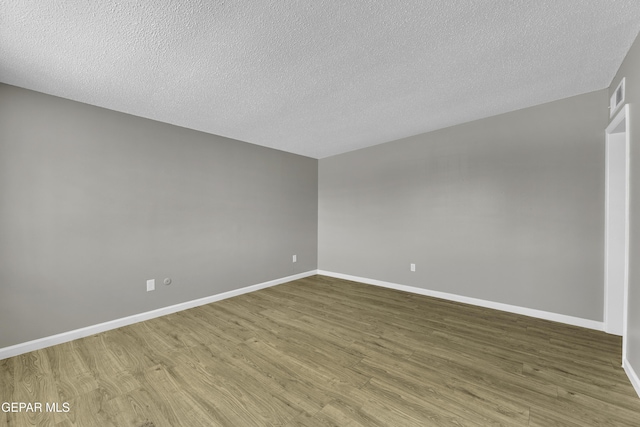 unfurnished room featuring wood-type flooring and a textured ceiling