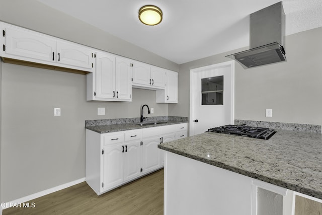 kitchen with sink, island range hood, gas cooktop, dark stone counters, and white cabinets