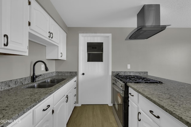 kitchen with island range hood, white cabinetry, sink, stainless steel gas range oven, and light wood-type flooring