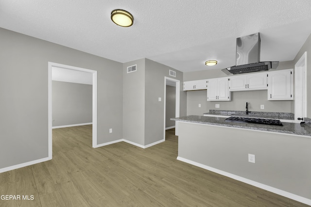 kitchen featuring white cabinetry, dark stone countertops, light hardwood / wood-style floors, a textured ceiling, and island exhaust hood