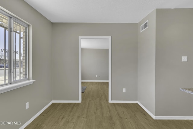 empty room with light hardwood / wood-style floors and a textured ceiling