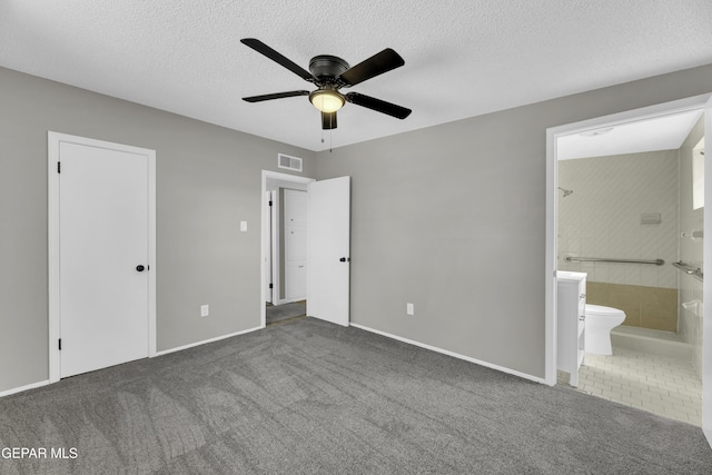 unfurnished bedroom featuring connected bathroom, a textured ceiling, dark carpet, a closet, and ceiling fan