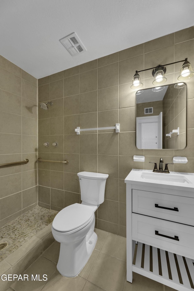 bathroom with tile patterned flooring, tiled shower, tile walls, and toilet