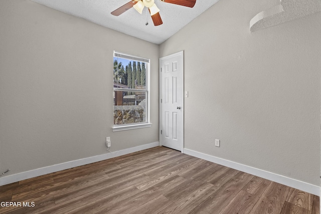 spare room featuring wood-type flooring, lofted ceiling, a textured ceiling, and ceiling fan