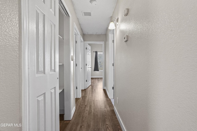 hallway featuring dark hardwood / wood-style floors and a textured ceiling