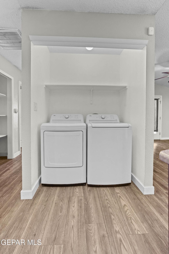 laundry room featuring washer and clothes dryer, light hardwood / wood-style floors, and a textured ceiling