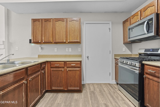 kitchen with stainless steel appliances, sink, and light hardwood / wood-style floors