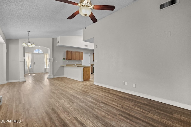 unfurnished living room featuring ceiling fan with notable chandelier, a textured ceiling, high vaulted ceiling, and light hardwood / wood-style floors