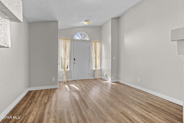 entrance foyer featuring lofted ceiling, hardwood / wood-style flooring, a wealth of natural light, and a textured ceiling