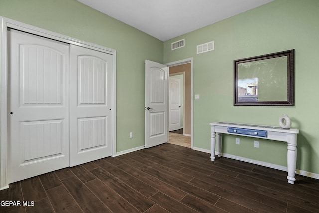 unfurnished bedroom with dark hardwood / wood-style flooring and a closet